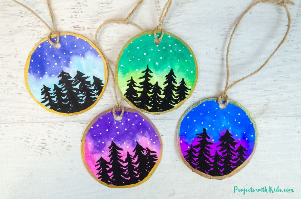 4 watercolor ornaments of a night sky, snow, and a forest