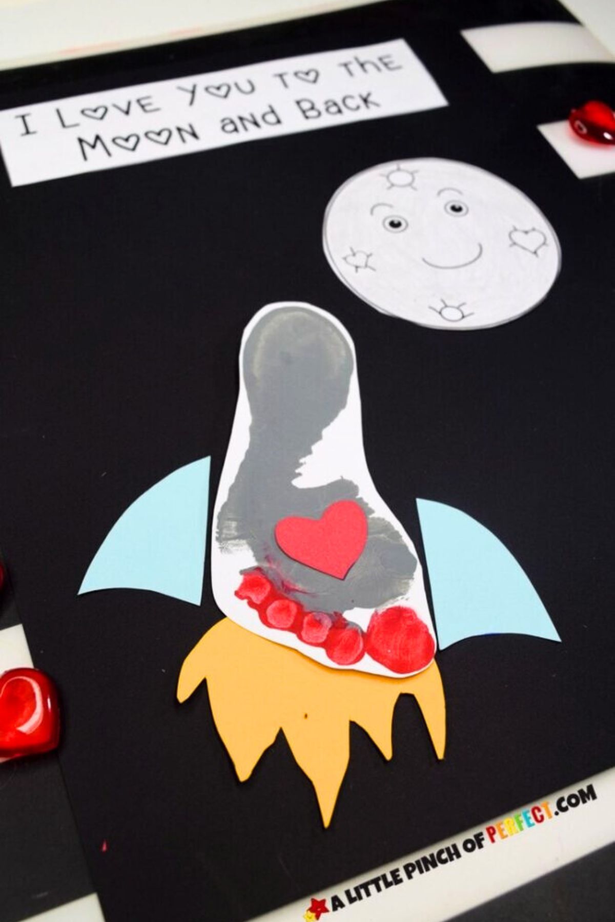 A child's footprint turned into a rocket ship with the words I love you to the moon and back at the top for a cute valentine's day craft