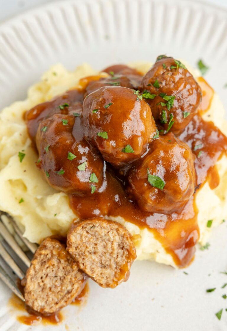 Slow cooker salisbury steak meatballs over a plate of mashed potatoes