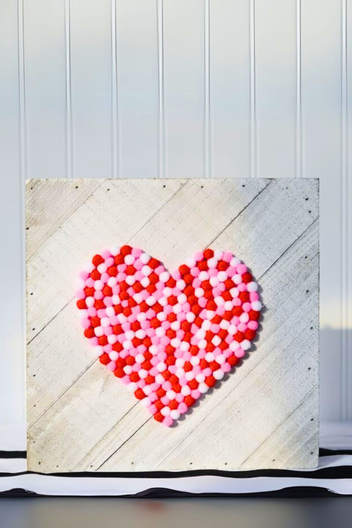 Valentine's Day pom-pom decor piece on wood